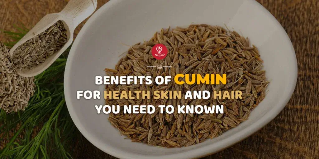 Wooden spoon filled with cumin seeds beside a glass of cumin water and fresh herbs, representing the health, digestion, metabolism, and skin benefits of cumin.